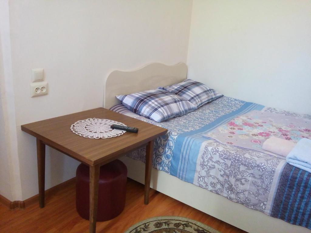 a small bed with a table with a remote on it at Guesthouse Mzeona in Batumi