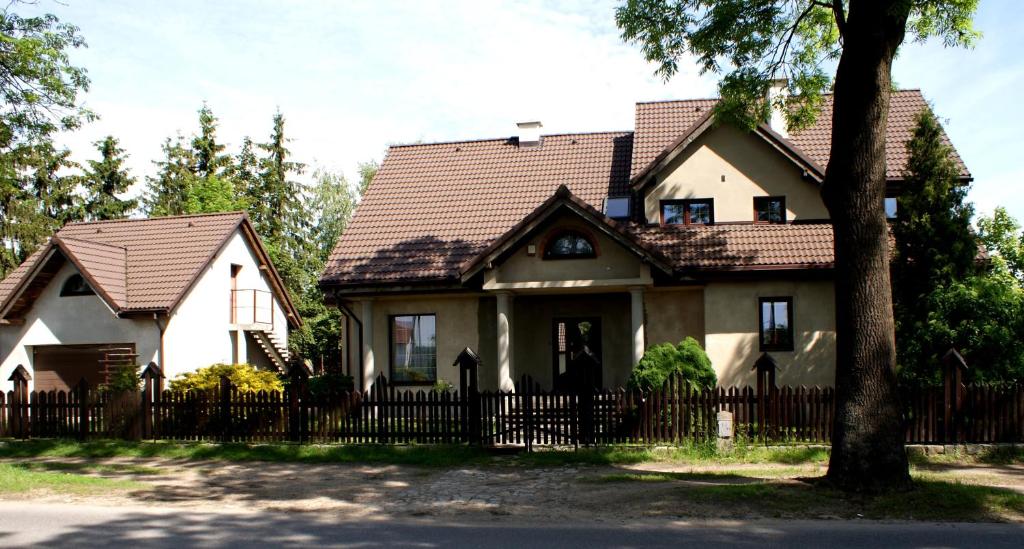 Piernikowy Dworek في Lubicz: منزل به سياج وشجر