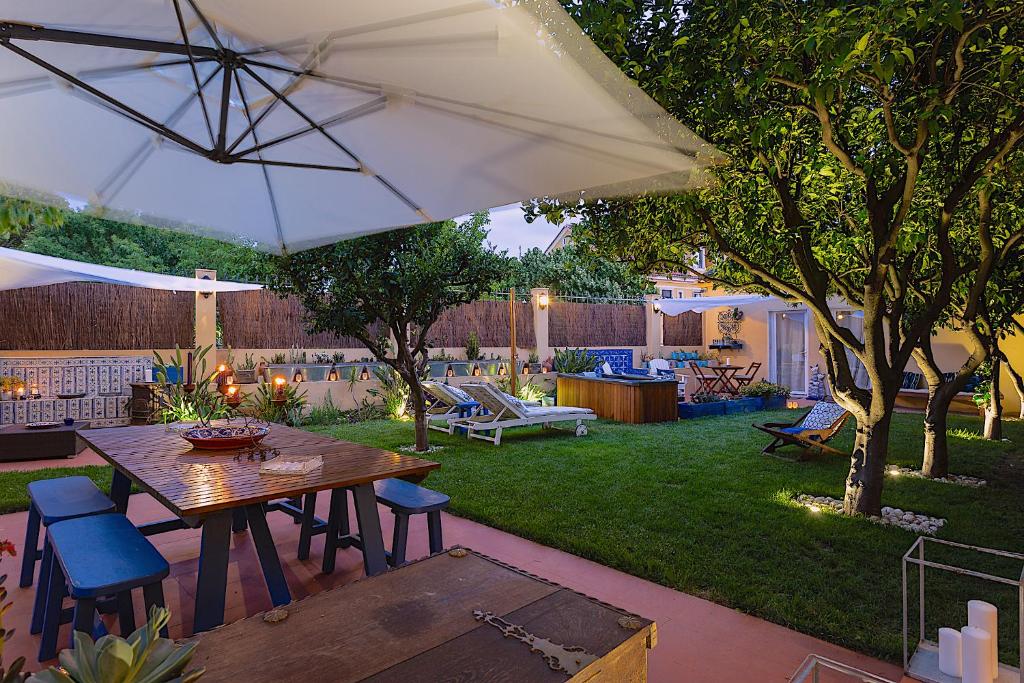 eine Terrasse mit einem Tisch, Stühlen und einem Sonnenschirm in der Unterkunft Geronimo Guest House Belém in Lissabon