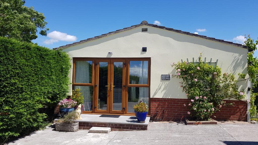 een klein huis met een grote glazen deur bij Rosehip Cottage in Somerton