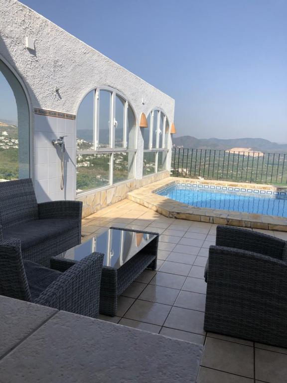 a house with a swimming pool and chairs and a swimming pool at Villa Luz del Monte in Denia