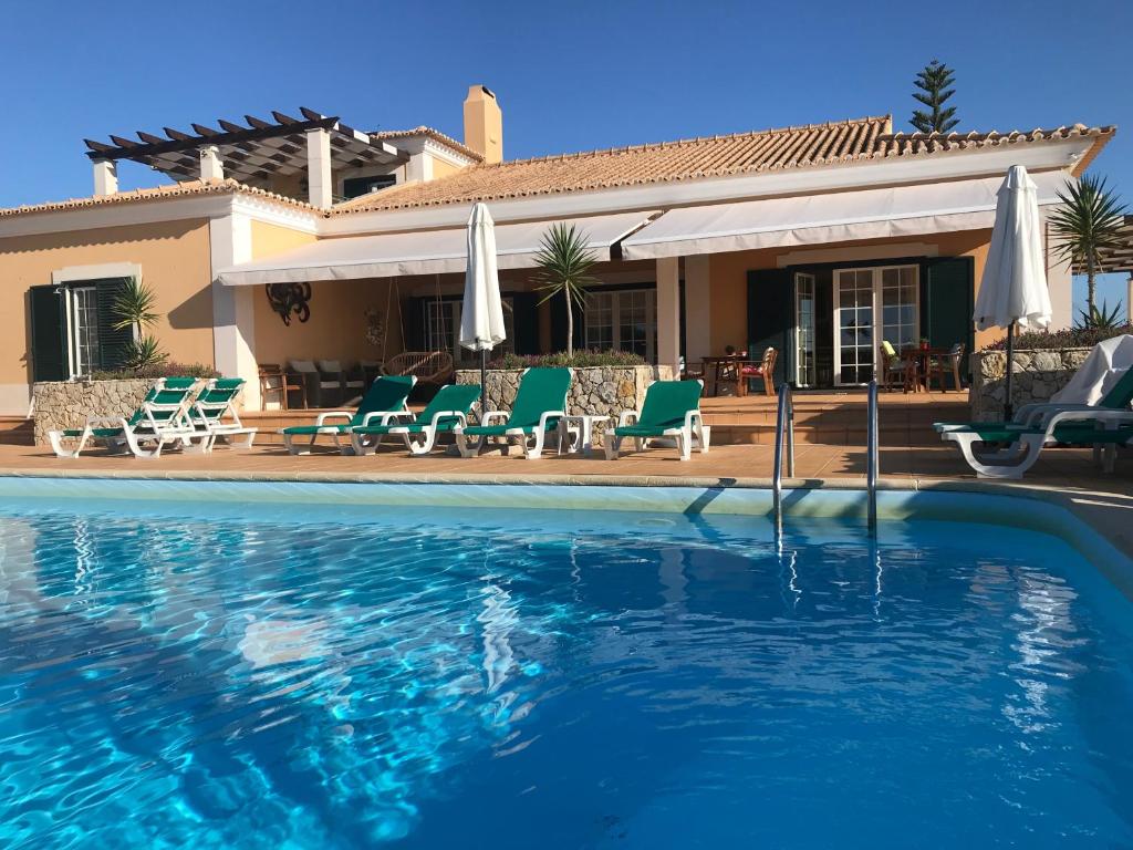 a swimming pool with chairs and a house at Casal das Oliveiras in Setúbal