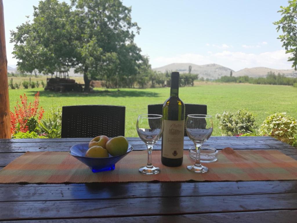 una mesa con una botella de vino y dos copas en Pensions Airport en Podgorica