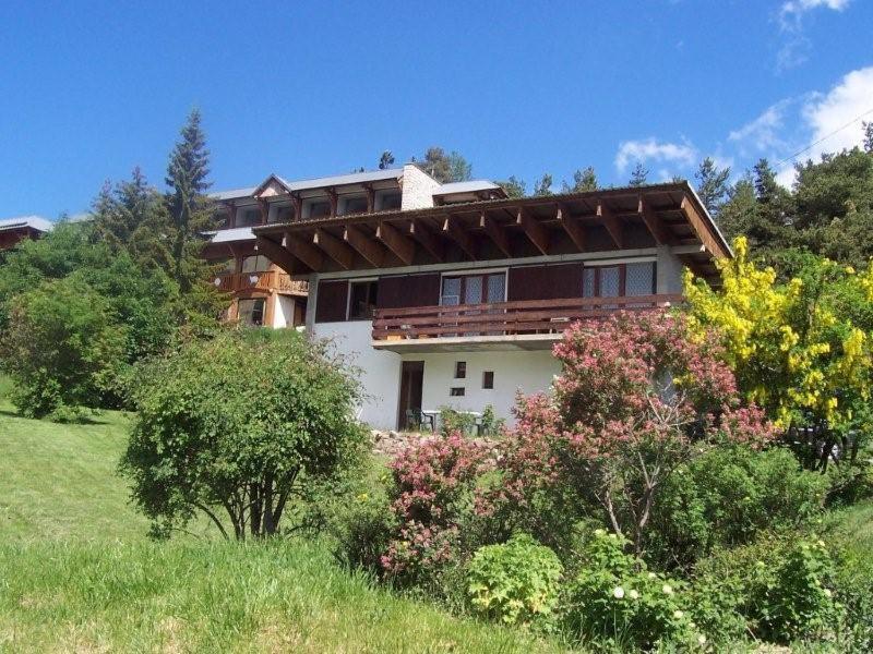 a large house on a hill with trees and bushes at Rdc Chalet in Pra-Loup