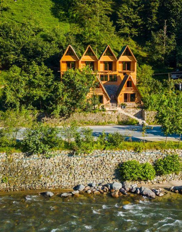 a large wooden house on a hill next to a river at ELASYA BUNGALOV in Rize