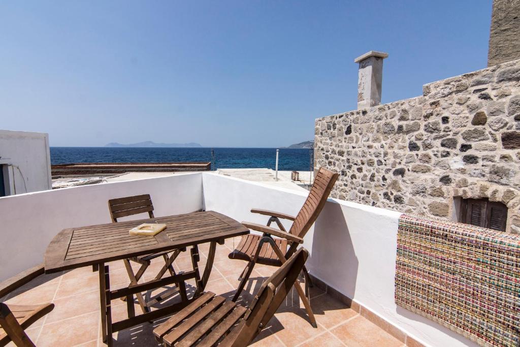 a table and chairs on a balcony with the ocean at Nisyros Views in Mandrakion