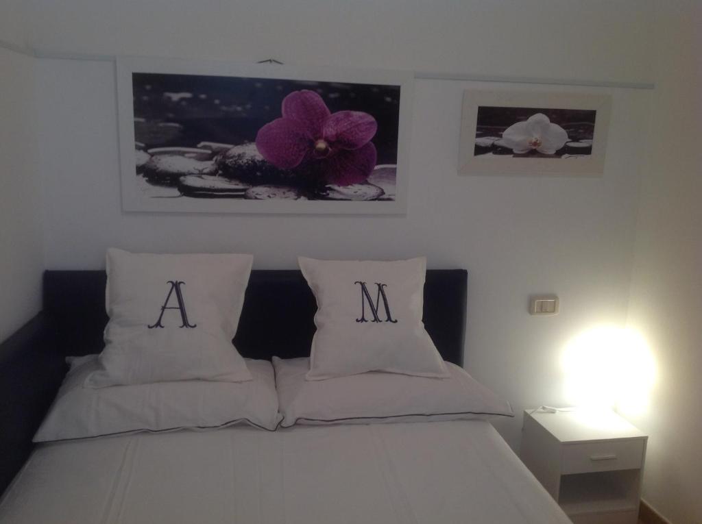 1 cama blanca con 2 almohadas y letras a y m en Appartamento Manuela, en Civitanova Marche