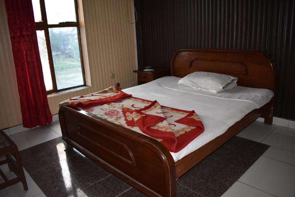 a bed with a wooden frame with a red blanket on it at Sitara Hotel in Islamabad