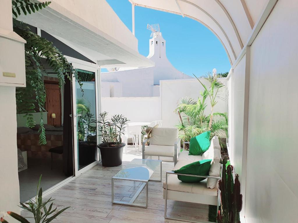プラヤ・デル・イングレスにあるBungalow 2-7 Playa del Inglesの白い家具と鉢植えの植物が備わるパティオ