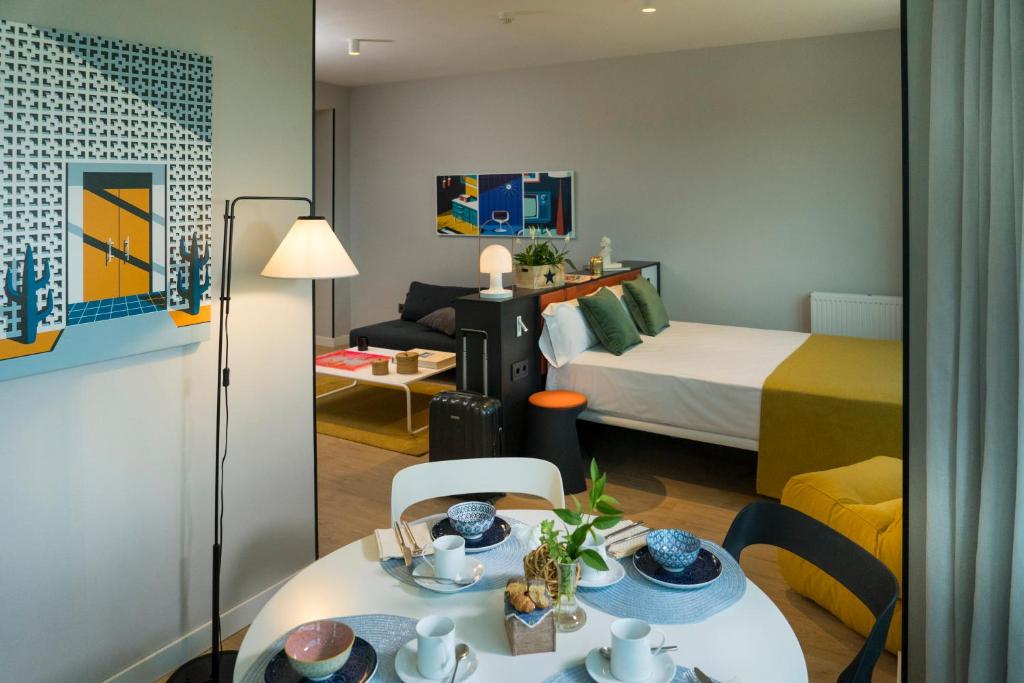 una camera d'albergo con letto, tavolo e sedie di The Oliver Apartamentos a Pozuelo de Alarcón