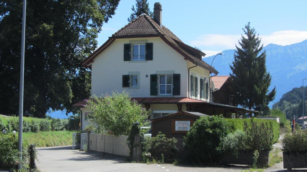 a white house with a brown roof at Bahnhöfli Faulensee in Faulensee