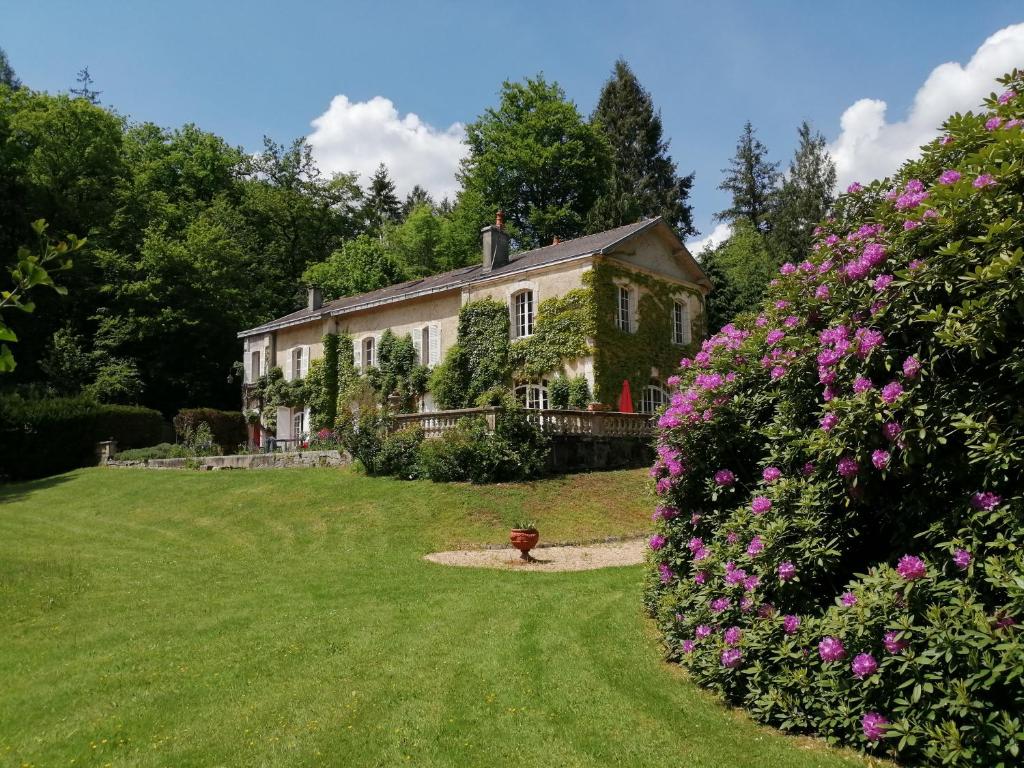 an old house with pink flowers in the yard at Domaine de La Brugere in Nantheuil