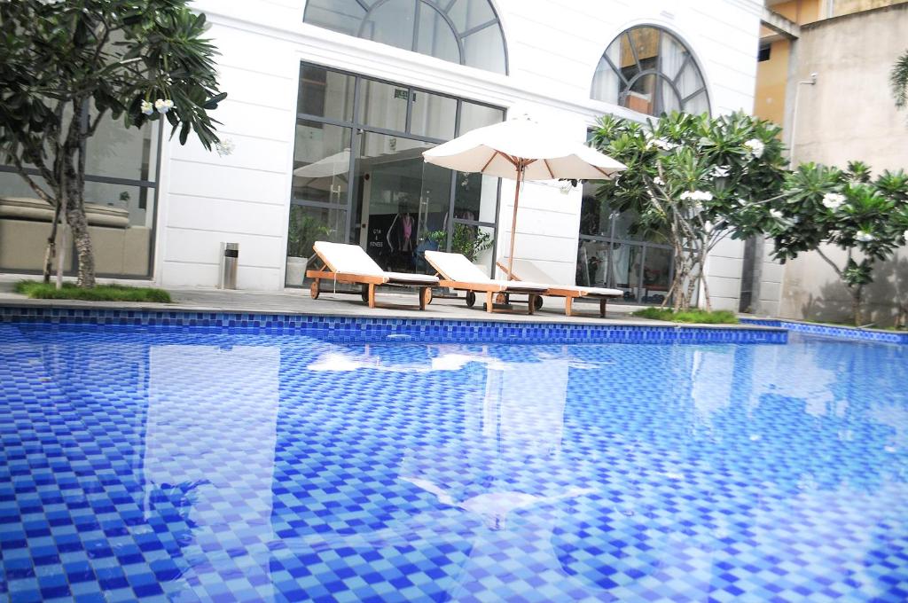a pool with two chairs and an umbrella next to a building at SAIGON GARDEN HILL Resort & Apartment in Ho Chi Minh City