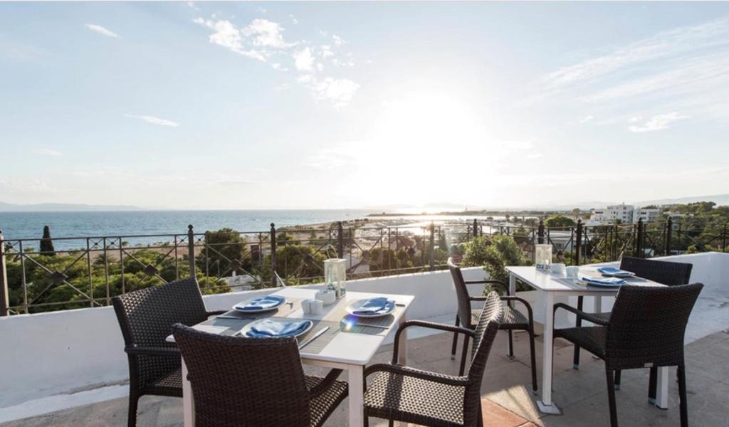 een tafel en stoelen op een balkon met uitzicht op de oceaan bij Hotel London in Athene