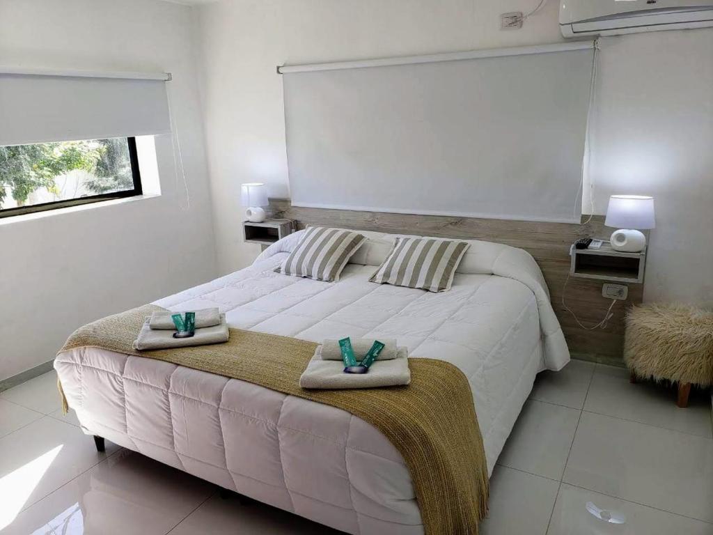 1 dormitorio con 1 cama blanca grande y toallas. en Hotel Pucará en La Rioja