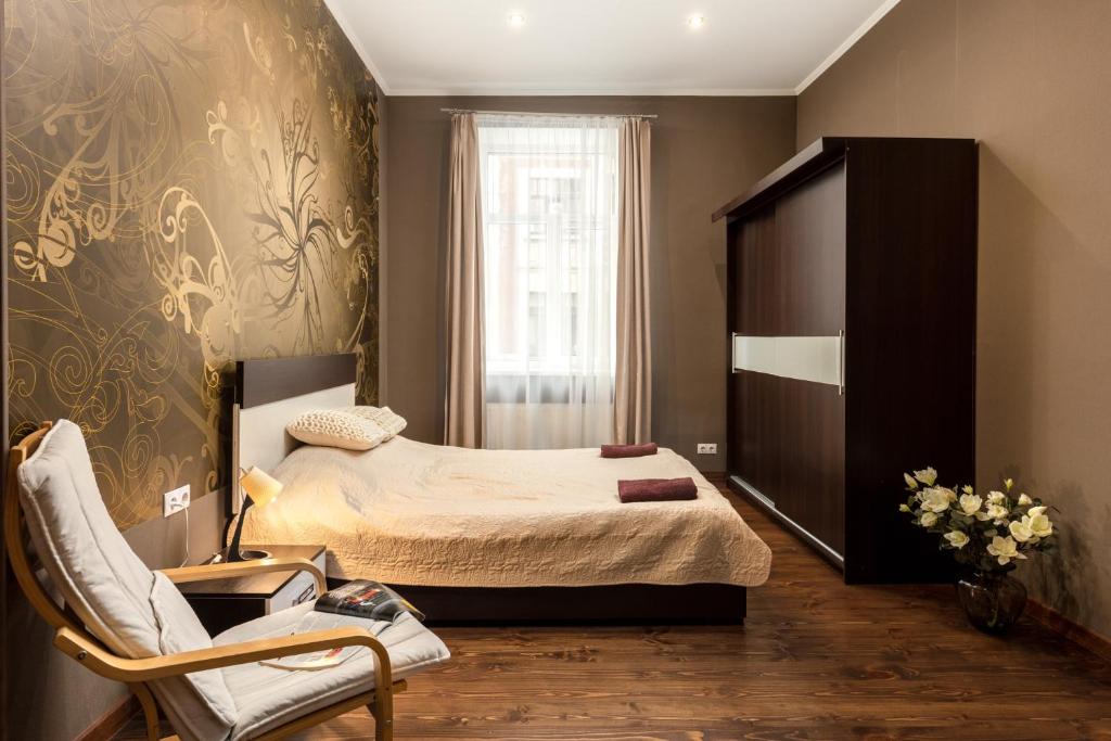 um pequeno quarto com uma cama e uma cadeira em Dagda Central apartment em Riga