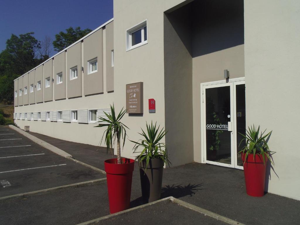 ein Gebäude mit zwei Topfpflanzen davor in der Unterkunft Good Hôtel Marseille Aubagne - La Valentine in La Penne-sur-Huveaune