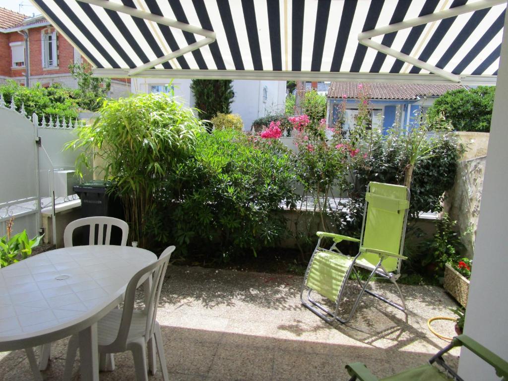 eine Terrasse mit einem Tisch und Stühlen unter einer Pergola in der Unterkunft Guillerette in Royan