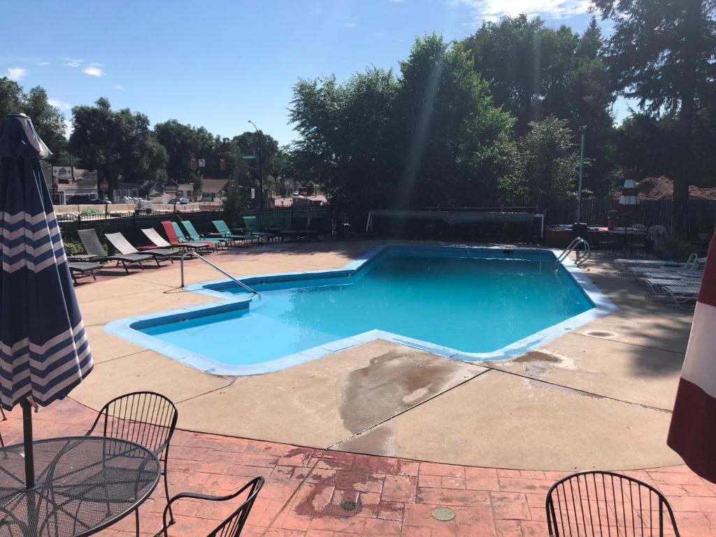 a large swimming pool with chairs and an umbrella at Rainbow Lodge and Inn in Colorado Springs
