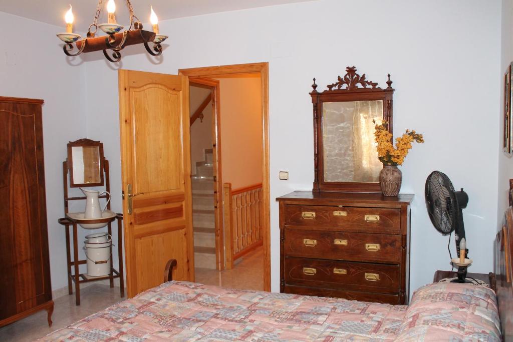 1 dormitorio con cama, tocador y espejo en Casa De La Virginia, en Valdealgorfa