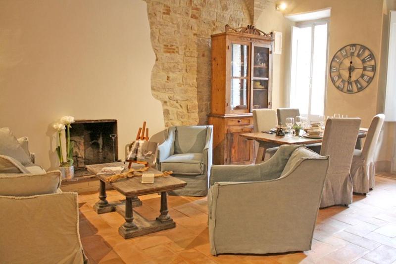 un soggiorno con tavolo, sedie e orologio di Il Rifugio dell' Artista a Todi