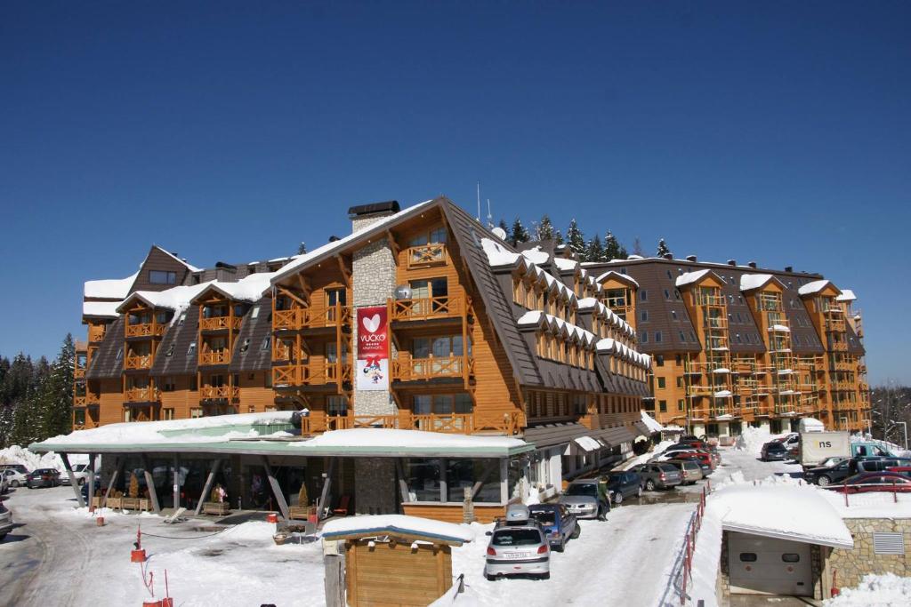 een groot gebouw met auto's geparkeerd op een parkeerplaats bij Apartments B137 & B027 - Aparthotel Vučko in Jahorina