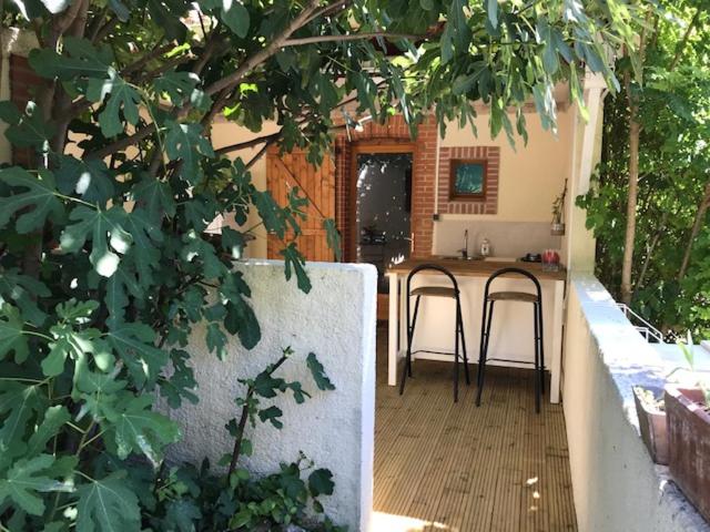un patio al aire libre con mesa y 2 taburetes en Les Fours à Chaux en Damiatte