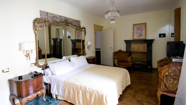 een slaapkamer met een groot bed en een spiegel bij Locanda degli Sfizi in Cravanzana