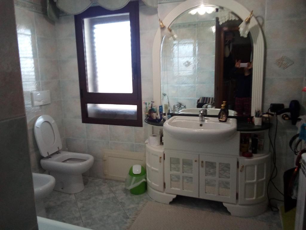 een badkamer met een wastafel, een toilet en een spiegel bij B&B is pranus a mari casa privata in Solanas