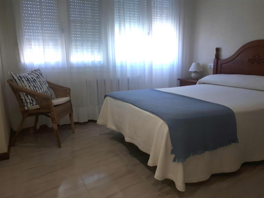 a bedroom with a bed and a chair and a window at AS VIÑAS in O Grove