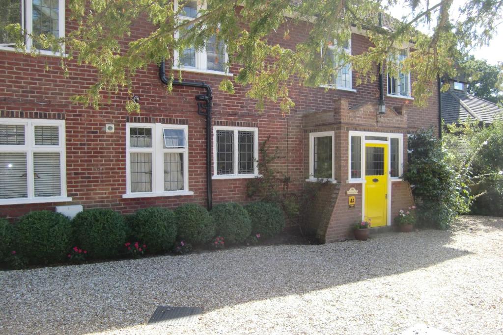 uma casa de tijolos com uma porta amarela em frente em Hatsue Guest House em Camberley