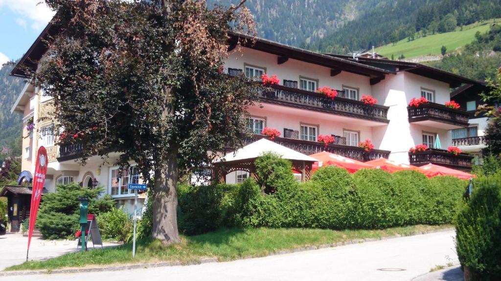 ein großes Gebäude mit roten Blumen auf den Balkonen in der Unterkunft Hotel zum Toni in Bad Hofgastein