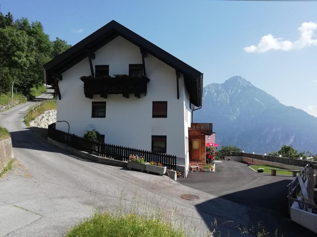 una casa blanca con techo negro en una carretera en Berghof Knabl en Arzl im Pitztal