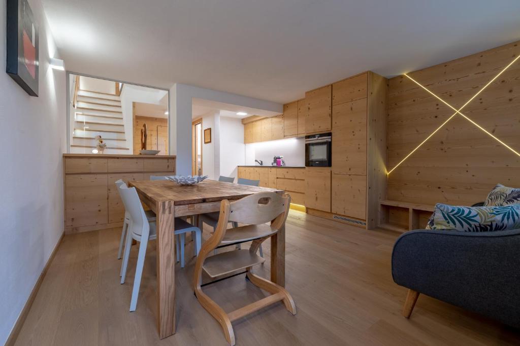 uma cozinha e sala de jantar com uma mesa de madeira e cadeiras em Chesa Silvretta Duplex em Celerina