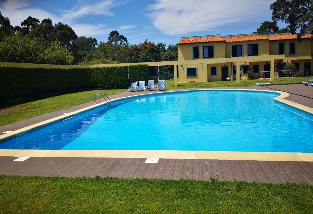 a pool with chairs and a house in the background at Quinta Da Boavista- Casa N in Caminha