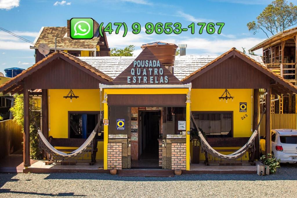 un edificio amarillo con un cartel. en Pousada Quatro Estrelas, en Penha