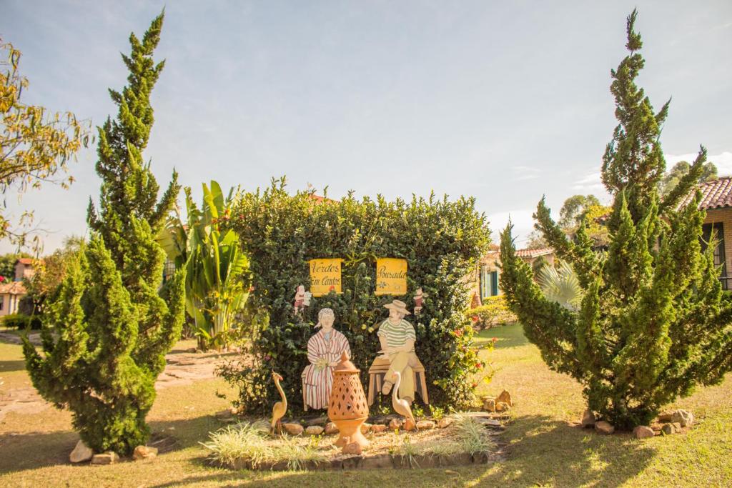 um grupo de pessoas sentadas num jardim com árvores em Verdes Em Cantos Pousada em Carrancas