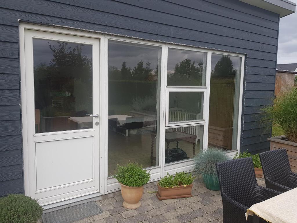 a sliding glass door on a house with plants at 1 room with private Bath in Allingåbro