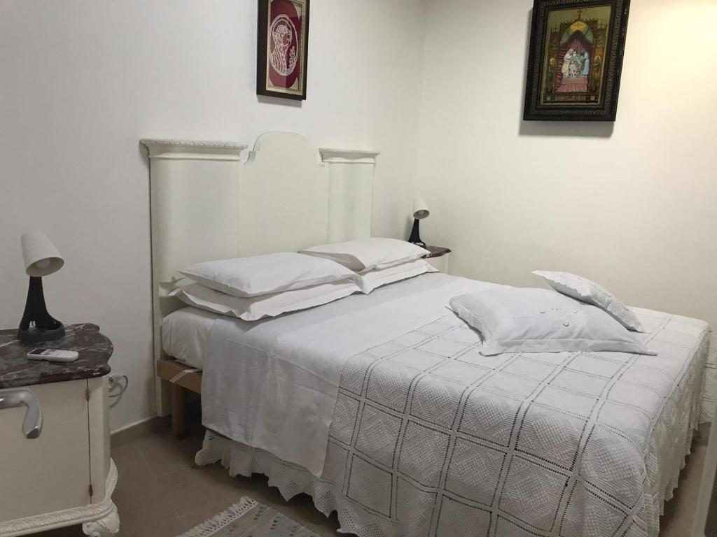 um quarto com uma cama com lençóis brancos e almofadas em A casa da Anita em Palazzolo Acreide