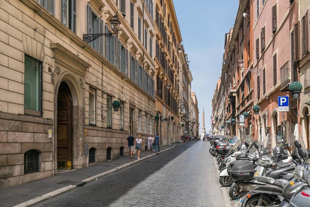 a street with a row of motorcycles parked next to buildings at Royal Piazza di Spagna in Rome