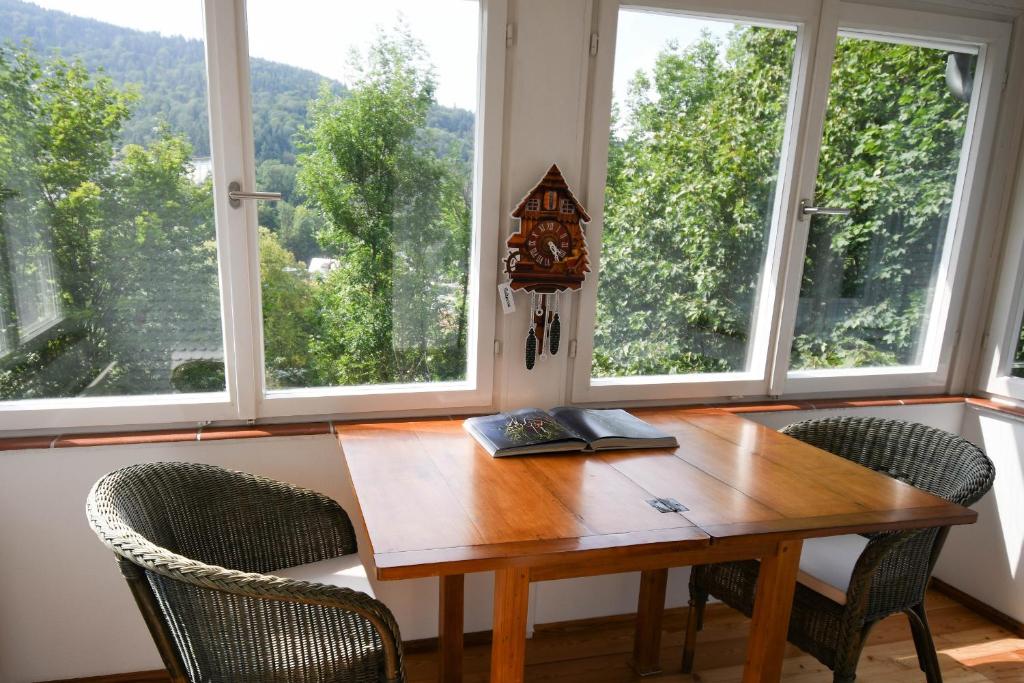 a wooden table with two chairs and two windows at Villa Sophie in Bad Herrenalb