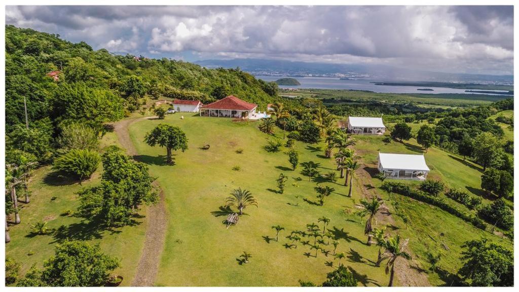 Vue aérienne d'une maison sur un champ verdoyant dans l'établissement Villa 1 de standing 80m2 avec piscine et vue imprenable sur la mer et sur la campagne, à Rivière-Salée