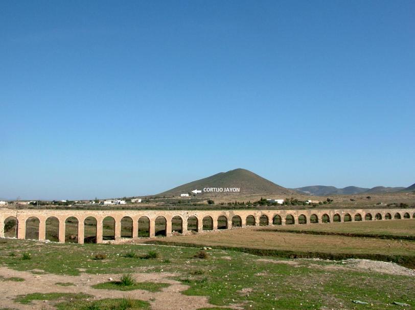 een lange brug in een veld met bergen op de achtergrond bij Cortijo Jayon in Fernán Pérez