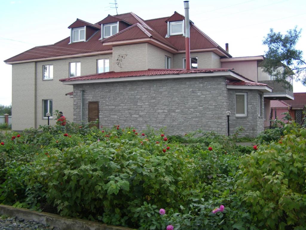 a large house with flowers in front of it at Guest House Kim House in Yuzhno-Sakhalinsk