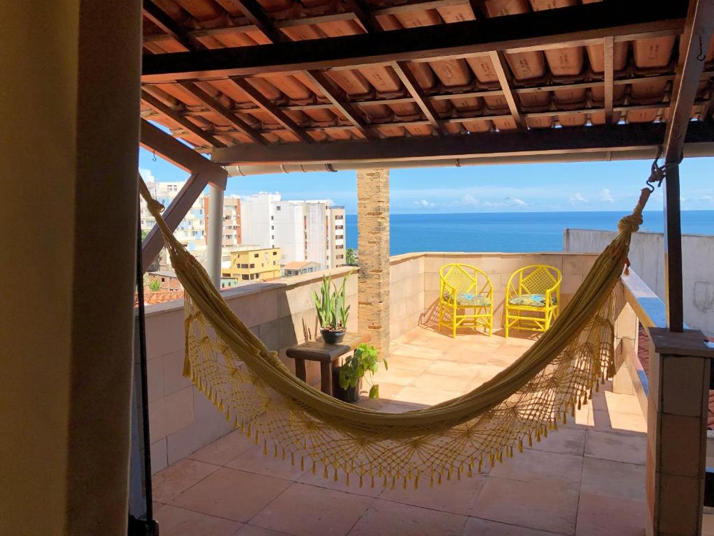 a hammock on a balcony with a view of the ocean at Villa Domenico in Salvador