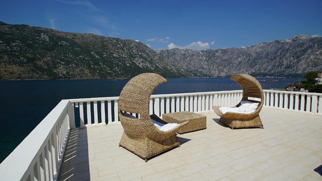 two chairs sitting on a deck next to the water at PENTHOUSE STOLIV New SPA-POOL Villa is located 5m from the sea, Exclusive Terrace,Private Jetty wih Sunbeds, Pebble Beach, Secluded location Total area 375m2 at your disposal in Kotor