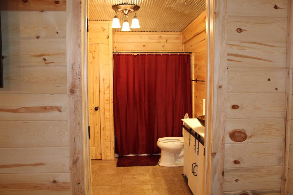 a bathroom with a toilet and a red shower curtain at Samantha's Timber Inn in Murfreesboro