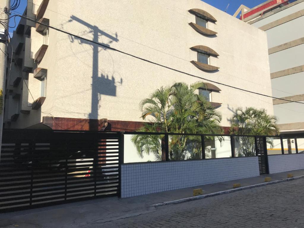 a building with a gate and a building with palm trees at Apartamento Praia do Forte - Cabo Frio in Cabo Frio