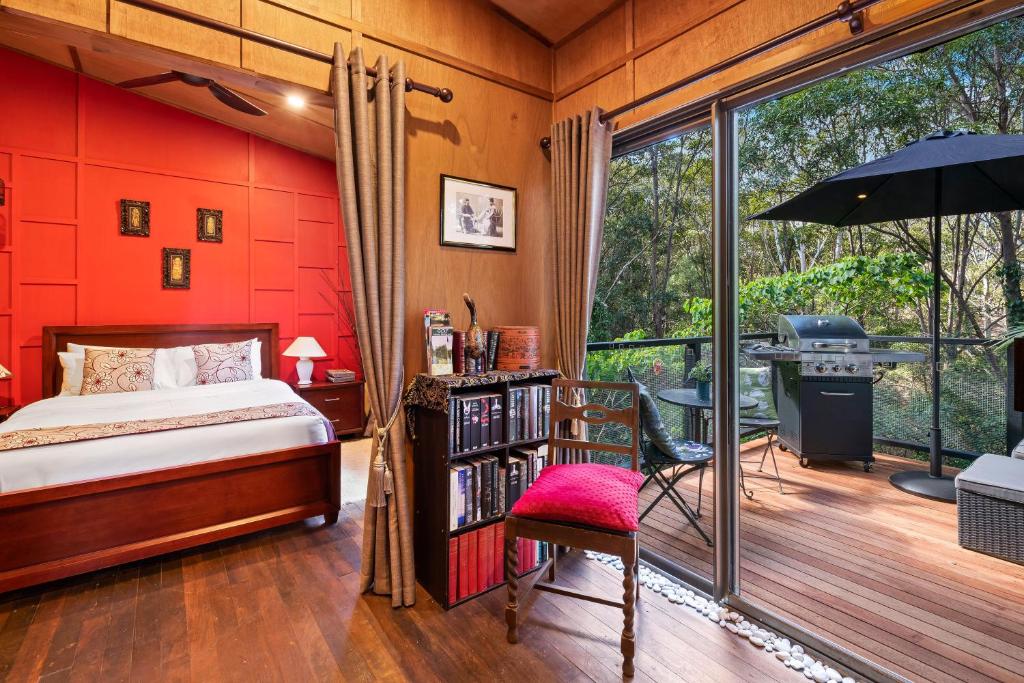 um quarto com paredes vermelhas, uma cama e uma varanda em Noosa Hinterland Retreat em Tinbeerwah