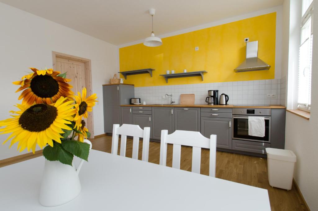 een keuken met een tafel met een vaas met zonnebloemen bij FeWo Markranstädt in Markranstädt